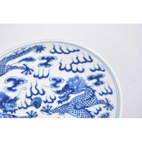 267 - A Chinese blue & white saucer dish, painted with two opposing dragons facing a flaming pearl amongst... 