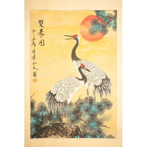 297 - A Chinese scroll painting of two Manchurian cranes, standing on a rock before a pine tree and blazin... 