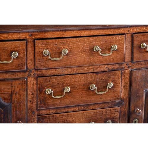 309 - A George III oak dresser and Delft rack fitted three open shelves above a base with three frieze dra... 