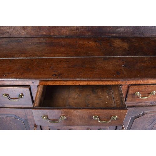 309 - A George III oak dresser and Delft rack fitted three open shelves above a base with three frieze dra... 