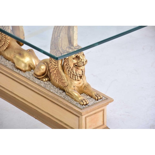 350 - An 'Egyptian Retour' glass-topped rectangular coffee table, 20th century, on gilt composition sphinx... 