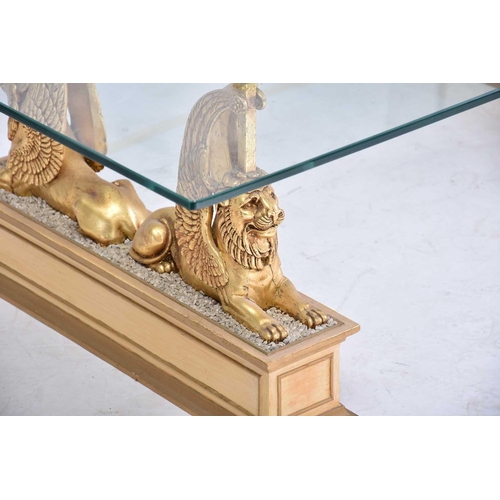 350 - An 'Egyptian Retour' glass-topped rectangular coffee table, 20th century, on gilt composition sphinx... 