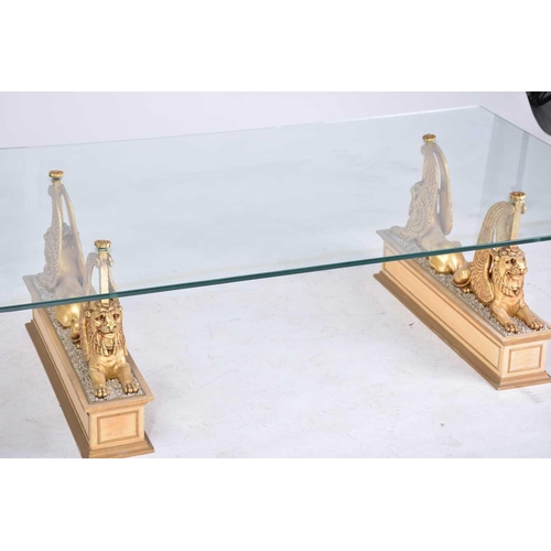 350 - An 'Egyptian Retour' glass-topped rectangular coffee table, 20th century, on gilt composition sphinx... 