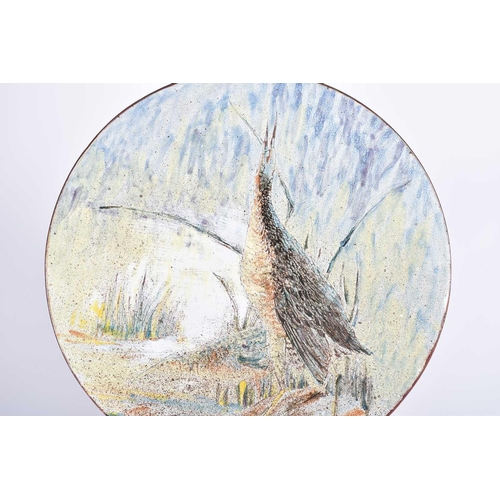 497 - A large Chelsea Pottery terracotta charger, painted with a wading bird by reeds and a stream, incise... 