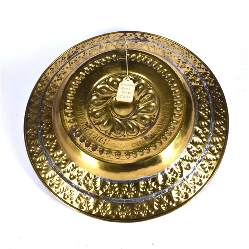 573 - A 17th century Nuremburg embossed brass alms dish, with central boss bordered by raised leaves and g... 