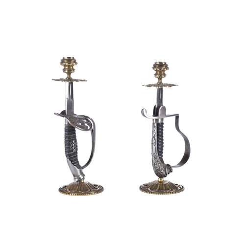 598 - A close pair of sword hilt candlesticks, one with lion head pommel and composite grip, the other wit... 