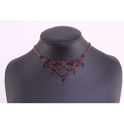 1 - A garnet and red paste garland necklace in gilt metal, with florets, five-pointed stars and teardrop... 