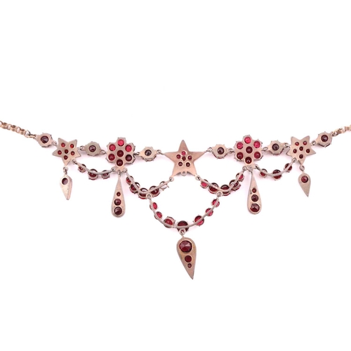 1 - A garnet and red paste garland necklace in gilt metal, with florets, five-pointed stars and teardrop... 