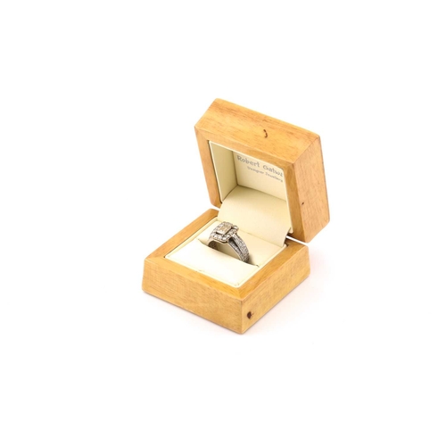 112 - A platinum and diamond entourage ring, featuring an emerald cut diamond in the centre with an approx... 