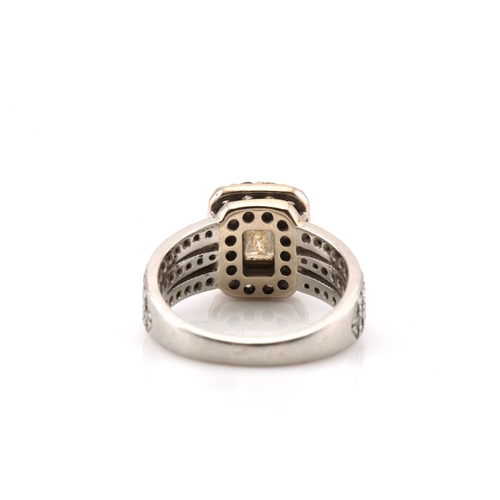 112 - A platinum and diamond entourage ring, featuring an emerald cut diamond in the centre with an approx... 