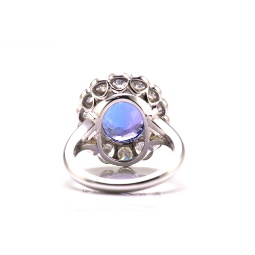 211 - A platinum tanzanite entourage ring, featuring an oval mixed-cut tanzanite with intense purplish-blu... 