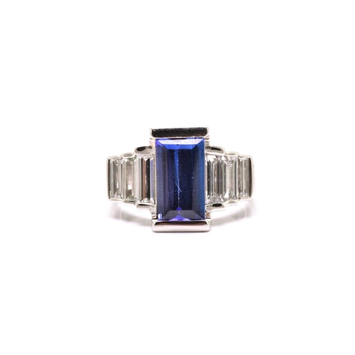 75 - An Art Deco-style platinum tanzanite and diamond ring, featuring a tapered rectangular step-cut tanz... 