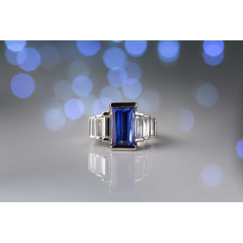 75 - An Art Deco-style platinum tanzanite and diamond ring, featuring a tapered rectangular step-cut tanz... 