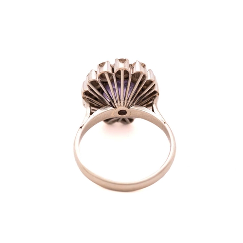 83 - A synthetic colour-changing sapphire and diamond cluster ring, centred with an oval cut synthetic co... 