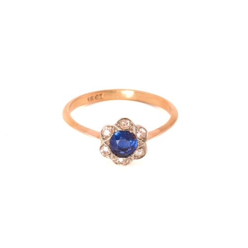 243 - A sapphire and diamond flower head ring, featuring a round sapphire claw set in the centre and surro... 