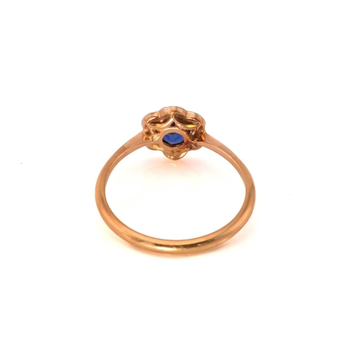 243 - A sapphire and diamond flower head ring, featuring a round sapphire claw set in the centre and surro... 