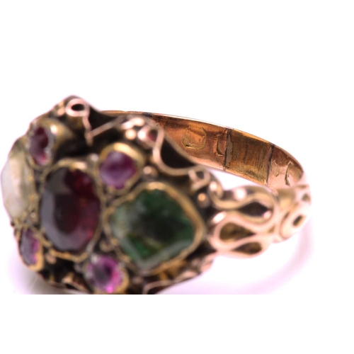 247 - A gem-set dress ring in yellow metal, featuring an oval cut garnet in the centre flanked by two foil... 