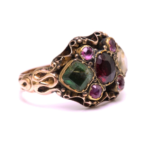 247 - A gem-set dress ring in yellow metal, featuring an oval cut garnet in the centre flanked by two foil... 