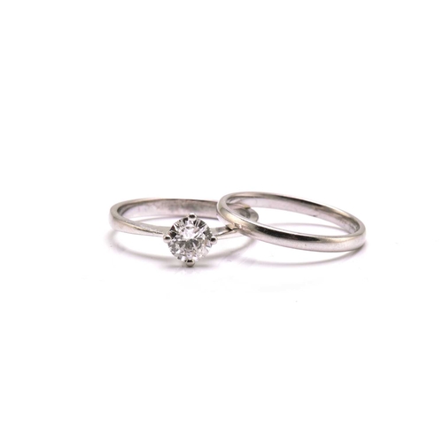 251 - A platinum diamond solitaire ring and platinum wedding band, the solitaire ring comprises a round br... 