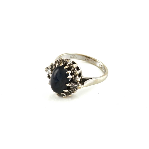 265 - A sapphire and diamond halo ring, featuring an oval sapphire high dome cabochon in dark blue colour,... 