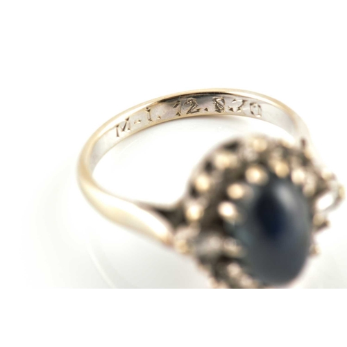 265 - A sapphire and diamond halo ring, featuring an oval sapphire high dome cabochon in dark blue colour,... 