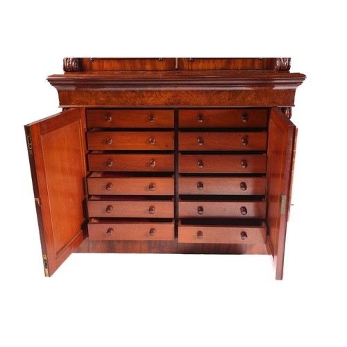 114 - A Victorian figured mahogany collectors cabinet bookcase. The upper section with a pair of shaped gl... 