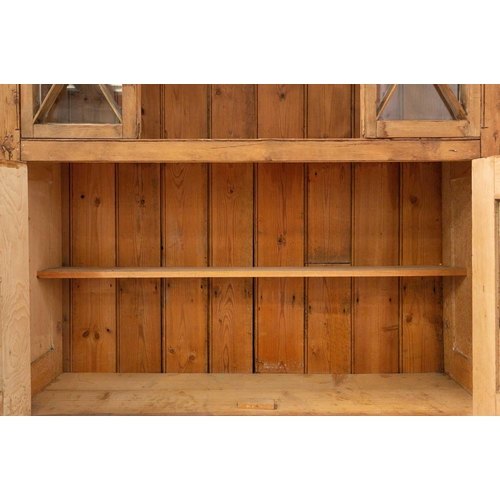 132 - An architectural stripped pine open cupboard bookcase with lattice glazed flanks above a pair of pan... 