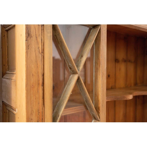 132 - An architectural stripped pine open cupboard bookcase with lattice glazed flanks above a pair of pan... 