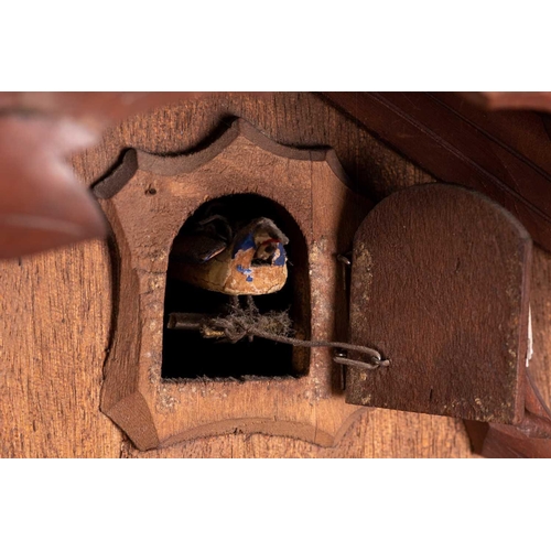 173 - An early 20th century carved walnut cuckoo wall clock with a pair of cast pine cone weights and leaf... 