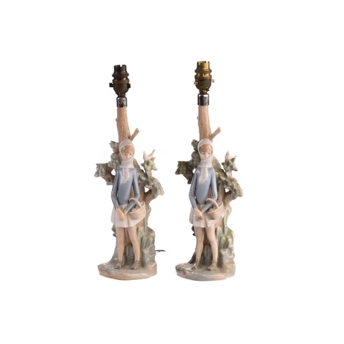 220 - Two Lladro figural table lamp bases, each modelled with a girl holding a basket, 39 cm high, togethe... 