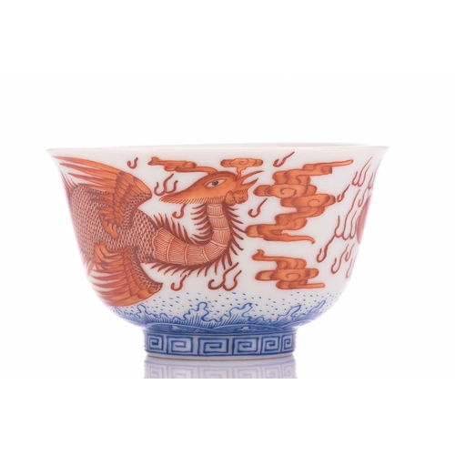 78 - A pair of Chinese porcelain bowls, painted in iron red, one with a dragon the other with a fenghuang... 