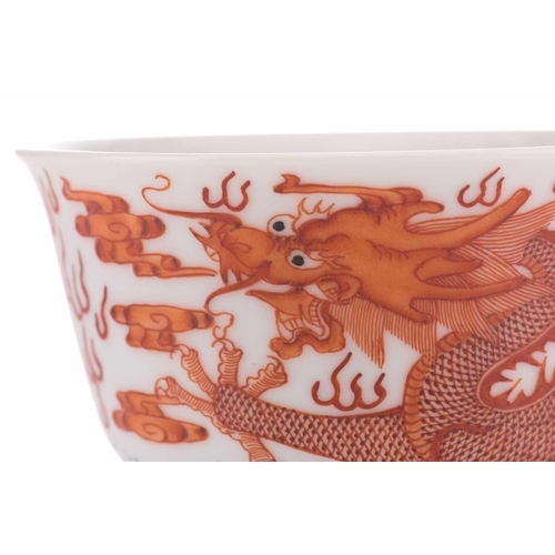 78 - A pair of Chinese porcelain bowls, painted in iron red, one with a dragon the other with a fenghuang... 