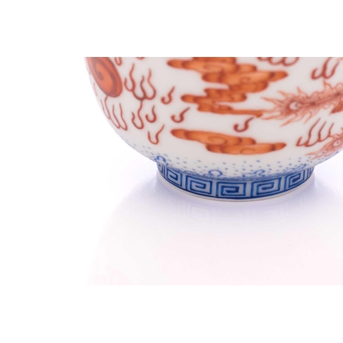 78 - A pair of Chinese porcelain bowls, painted in iron red, one with a dragon the other with a fenghuang... 