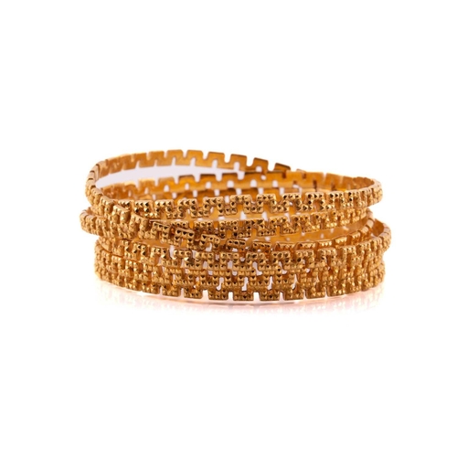 60 - A suite of six meander bangles, with a diamond stud pattern texture on the exterior, yellow metal un... 