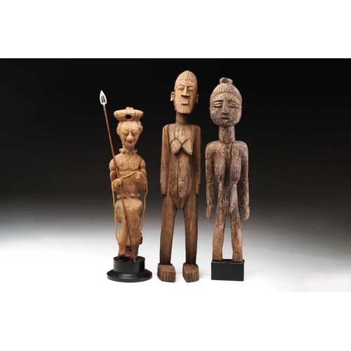 92 - An Indonesian standing female figure, the linear coiffure terminating in a curl, on a wood base, and... 