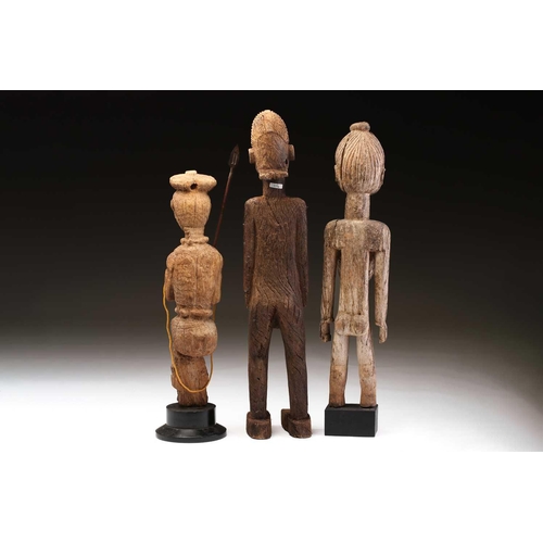 92 - An Indonesian standing female figure, the linear coiffure terminating in a curl, on a wood base, and... 