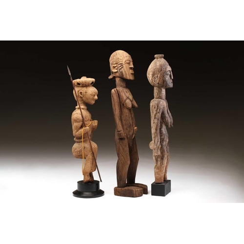 92 - An Indonesian standing female figure, the linear coiffure terminating in a curl, on a wood base, and... 