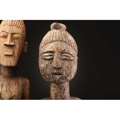 92 - An Indonesian standing female figure, the linear coiffure terminating in a curl, on a wood base, and... 