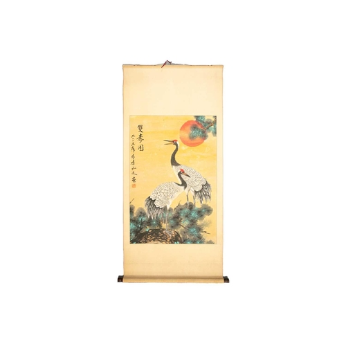 196 - A Chinese scroll painting of two Manchurian cranes, standing on a rock before a pine tree and blazin... 