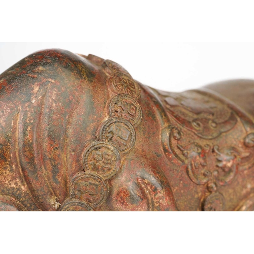 198 - A Chinese bronze figure of a charging bull, wearing a band of good luck charms, traces of red pigmen... 