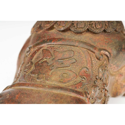 198 - A Chinese bronze figure of a charging bull, wearing a band of good luck charms, traces of red pigmen... 