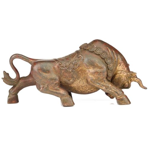 198 - A Chinese bronze figure of a charging bull, wearing a band of good luck charms, traces of red pigmen... 