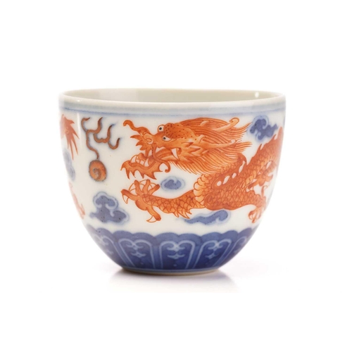 136 - A Chinese porcelain tea bowl and stand, painted with iron red dragons facing a flaming pearl amongst... 