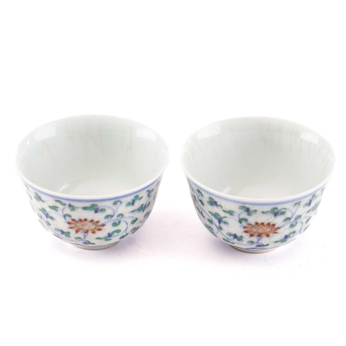 153 - A pair of Chinese Wucai tea bowls, painted with lotus flowers and leafy scrolling fronds above a ruy... 