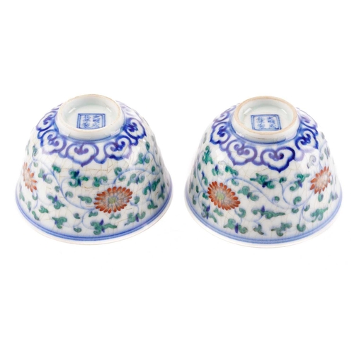 153 - A pair of Chinese Wucai tea bowls, painted with lotus flowers and leafy scrolling fronds above a ruy... 