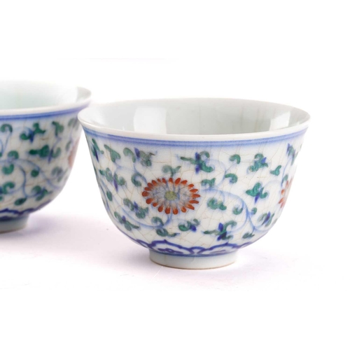 153 - A pair of Chinese Wucai tea bowls, painted with lotus flowers and leafy scrolling fronds above a ruy... 