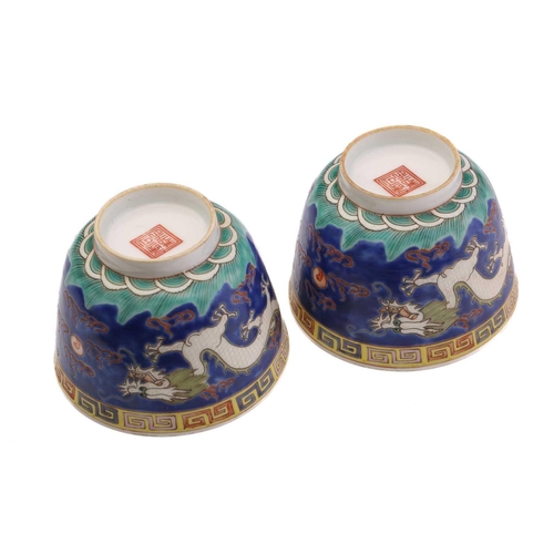 175 - A pair of Chinese porcelain dragon cups, painted with opposing white dragons facing a pearl amongst ... 