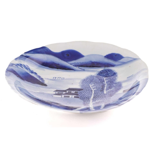 179 - A Japanese blue & white dish, 18th/19th century, painted with a landscape, with a shaped rim, the un... 