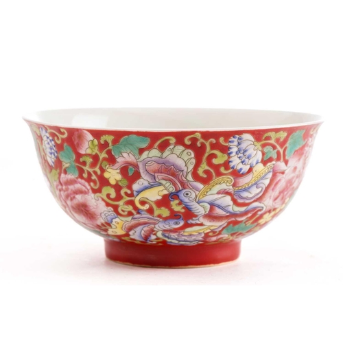 205 - A Chinese porcelain bowl, painted with butterflies amongst flower and leafy tendrils against a red g... 