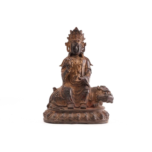 211 - A Chinese bronze figure of Guanyin, in the Ming style, seated in vitarka mudra upon a temple lion on... 